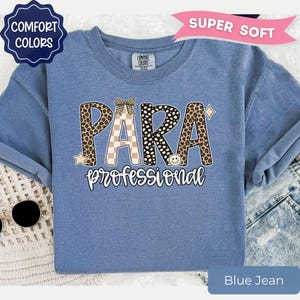 May include: A blue short-sleeved t-shirt featuring the text PARA in large letters with leopard print and checkered patterns, topped with a small bow. Below, the word professional is written in white script. Includes star and smiley face icons.