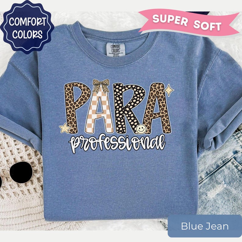 May include: A blue short-sleeved t-shirt featuring the text PARA in large letters with leopard print and checkered patterns, topped with a small bow. Below, the word professional is written in white script. Includes star and smiley face icons.