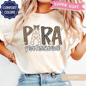 May include: An ivory t-shirt featuring the text PARA in large letters with leopard print and checkered patterns, topped with a small bow graphic. Below, the word professional is written in black script. Decorative stars and a smiley face are included.