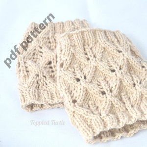 May include: A pair of beige knitted leg warmers with a lacy pattern. The leg warmers are made with a soft yarn and have a comfortable fit. The image includes the text "pdf pattern" and "Toppled Turtle".