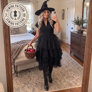May include: A black dress with a V-neckline and a multi-layered tulle skirt featuring lace trim. The outfit includes a black pointed witch hat and black knee-high boots. A brown woven basket containing red apples is held in one hand.