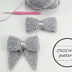 May include: Two silver crochet bows with a matching ball of yarn, a pink crochet hook, and the text "CROCHET pattern" in a circle. The bows are made of a shiny, metallic yarn. The items are arranged on a white surface.