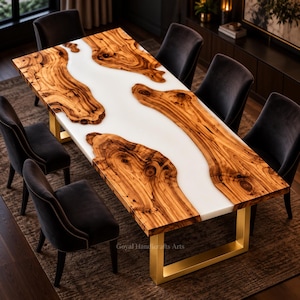 Könnte beinhalten: Ein rechteckiger Esstisch mit einer Massivholzplatte mit Naturkante und einem mittigen Inlay aus weißem Kunstharz. Der Tisch steht auf zwei goldfarbenen, U-förmigen Metallbeinen und ist von sechs dunkelgrauen Stühlen aus Samt umgeben.