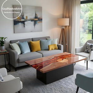 May include: A rectangular coffee table with a wood and resin top, on a black base. The wood grain is visible, with red and orange resin accents. The table is in a living room setting with a grey sofa and colourful cushions.