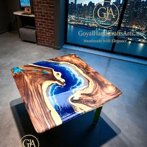 May include: Square wooden coffee table with a blue and white resin river design. The table has a natural wood grain border and green legs. The table is handmade with elegance. The table is in a room with a city view.