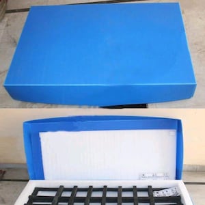 May include: Blue packing box with the text "PACKING BOX" at the top. The box is shown closed and open, revealing white foam padding and a black grid-like structure inside. The box is made of a durable material.