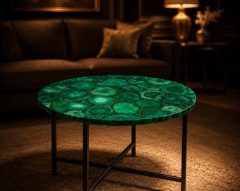 May include: A round coffee table with a vibrant green agate stone top. The table has a dark metal frame with a cross-legged base. The table is approximately 36 inches in diameter and is a striking piece of furniture.