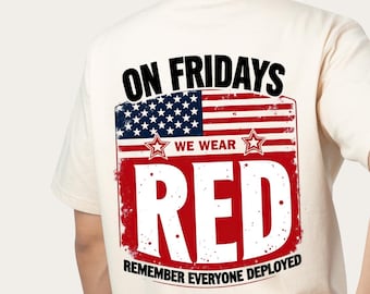May include: Cream-colored t-shirt with a graphic on the back. The graphic features the American flag, the words "ON FRIDAYS WE WEAR RED" and "REMEMBER EVERYONE DEPLOYED".