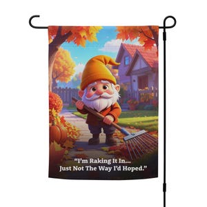 Peut inclure: Un drapeau de jardin avec un gnome de dessin animé ratissant des feuilles dans une scène d'automne. Le gnome porte un chapeau et une veste orange, tenant un râteau. Le texte dit : « I'm Raking It In... Just Not The Way I'd Hoped. » L'arrière-plan montre une maison et des feuilles d'automne.