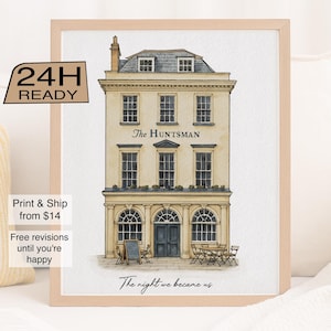 May include: Watercolor print of a building with the text "The Huntsman" above the entrance. The building is beige with dark blue doors and windows. The text "The night we became us" is below the building. The print is framed in a light wood frame.