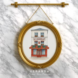 Könnte beinhalten: Ein ovaler, goldgerahmter Druck einer Aquarellillustration eines Cafés, "Le Consulat". Das Café hat eine rot-grüne Markise und wird von einer goldenen Kette an einer goldenen Stange aufgehängt. Der Hintergrund ist eine Marmorwand.