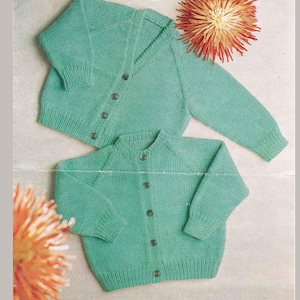 Op de afbeelding: Twee mintgroene gebreide vesten met knoopsluiting. Eén vest heeft een V-hals, de andere een ronde hals. De vesten worden gepresenteerd op een lichte achtergrond met oranje en gele bloemaccenten.