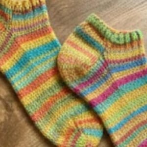 May include: A pair of colorful, hand-knitted socks. The socks feature horizontal stripes in a variety of colors, including yellow, orange, red, blue, and green. The socks are made of a soft, textured yarn and appear to be ankle-length.