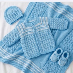 May include: A baby blue knitted layette set, including a cardigan, hat, blanket, and booties. The cardigan and hat have a textured pattern, with white stripes on the cardigan. The blanket and booties are also baby blue.