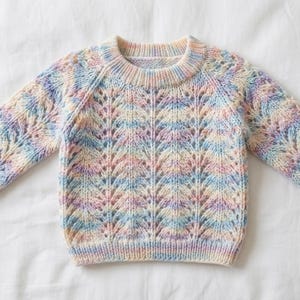 May include: A pastel-coloured knitted jumper with a round neckline and long sleeves. The jumper features a delicate openwork pattern in shades of blue, pink, yellow, and cream. The garment is made of soft yarn and is suitable for children.