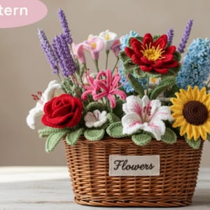 May include: A handmade crochet floral display in a wicker basket. The bouquet includes a red rose, white lilies, a yellow sunflower, and lavender. The basket has a label that reads "Flowers". The flowers are made with yarn.