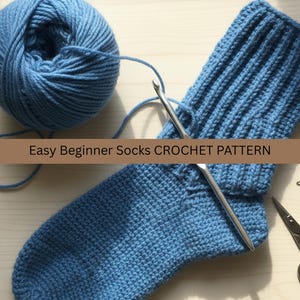 Puede incluir: Un calcetín azul tejido a ganchillo con una madeja de lana azul, un ganchillo, unas tijeras y un marcador de punto. El texto "Easy Beginner Socks CROCHET PATTERN" se muestra en una pancarta marrón.
