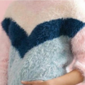 May include: A fluffy, multi-colored sweater with a chevron design. The sweater features a color block pattern with pink, white, blue, and light blue sections. The soft, textured material creates a cozy and stylish look.