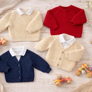 Puede incluir: Cuatro suéteres infantiles en crema, rojo y azul marino. Dos suéteres tienen camisas blancas con cuello debajo. Coches de juguete de madera y decoraciones en forma de estrella están esparcidos alrededor de los suéteres. Los suéteres son de punto.