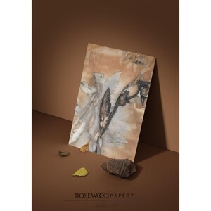 May include: A rectangular art print featuring an abstract botanical design with muted brown, tan, and grey tones. The print displays organic leaf-like shapes and dark, textured markings across the surface, creating a natural, earthy aesthetic.