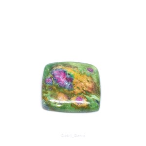 May include: A square gemstone with a polished surface. The stone displays a mix of colours, including green, yellow, and pink. The pink areas are concentrated in the centre, while the green and yellow hues are more spread out.