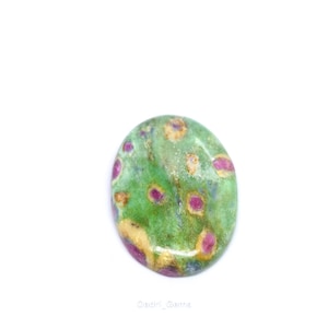 May include: Oval-shaped gemstone with a green base color, speckled with red and tan spots. The polished stone has a smooth surface and is set against a white background. The gemstone is likely a cabochon.