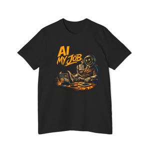 May include: Black t-shirt with an illustration of an astronaut at a desk with a laptop and coffee mug. The text "AI MY JOB" is in orange. The astronaut is wearing a helmet with a smiley face.