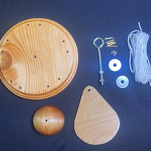 Peut inclure: Un kit de bricolage en bois avec une base ronde, une pièce en forme de goutte et un bouton sphérique. Comprend des vis, des rondelles, un boulon à œil métallique et de la ficelle blanche. Le bois a une finition brun clair naturelle.