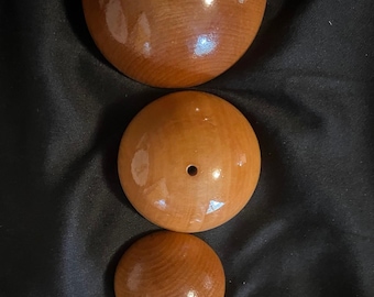 May include: Four wooden spheres of varying sizes, arranged vertically. Each sphere is a warm brown color with a glossy finish and a small hole drilled through the center. The wood grain is visible.