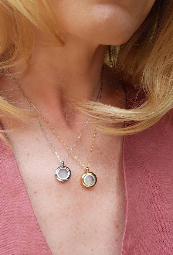 A tiny round glass locket with a screw-top vial you can fill with ashes, mementos, or floating charms — a deeply personal wearable keepsake with 119 favorites backing the demand.