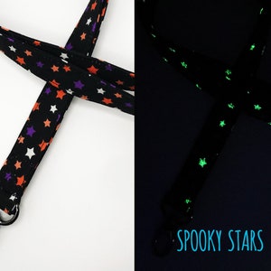May include: Black lanyard with orange, purple, and white stars. The lanyard has a metal clasp and the text "Spooky Stars". The stars glow in the dark.