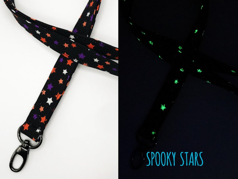 May include: Black lanyard with orange, purple, and white stars. The lanyard has a metal clasp and the text "Spooky Stars". The stars glow in the dark.