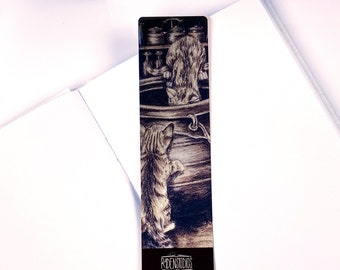May include: A rectangular bookmark featuring a sepia-toned illustration of two kittens near a pot. One kitten is inside the pot, and the other is looking in. The bottom of the bookmark has the text "RAIDENSTUDIOS".