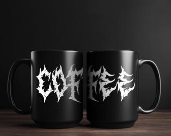 May include: Two black ceramic mugs with a white, stylized text design. The text appears to be a band name or logo. The mugs are on a dark wooden surface with a black background.