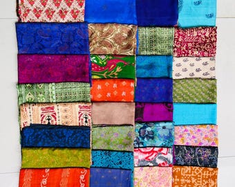 May include: A collection of folded fabric pieces in various colors and patterns. The assortment includes vibrant hues like blue, orange, and pink, with designs ranging from floral to geometric. The textiles are neatly arranged, showcasing a diverse array of textures and styles.