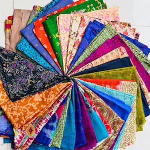 Può includere: Una disposizione circolare di ritagli di tessuto colorati, che mostra una varietà di motivi e trame. I tessuti includono sfumature di blu, verde, arancione, rosa e viola, con disegni floreali e geometrici. La disposizione è a ventaglio, mostrando i bordi di ogni pezzo.