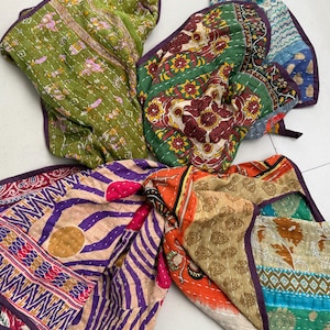 Puede incluir: Una colección de coloridas colchas kantha estampadas. Las colchas presentan varios diseños, incluyendo motivos florales, geométricos y animales, con una textura cosida y bordes morados. La paleta de colores incluye verde, naranja, morado y beige.