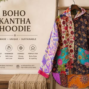 May include: A long-sleeve hooded jacket featuring a patchwork design with various floral and paisley patterns in vibrant colors including purple, orange, red, and teal. The garment has two front pockets and a curved hemline, hanging on a wooden hanger.