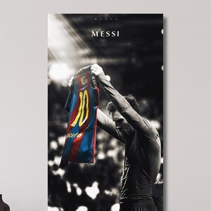 May include: A vertical wall art print featuring a black and white photograph of a soccer player holding up a blue, red, and yellow jersey with the number 10. The text MESSI is printed in white at the top center against a dark, stadium-lit background.