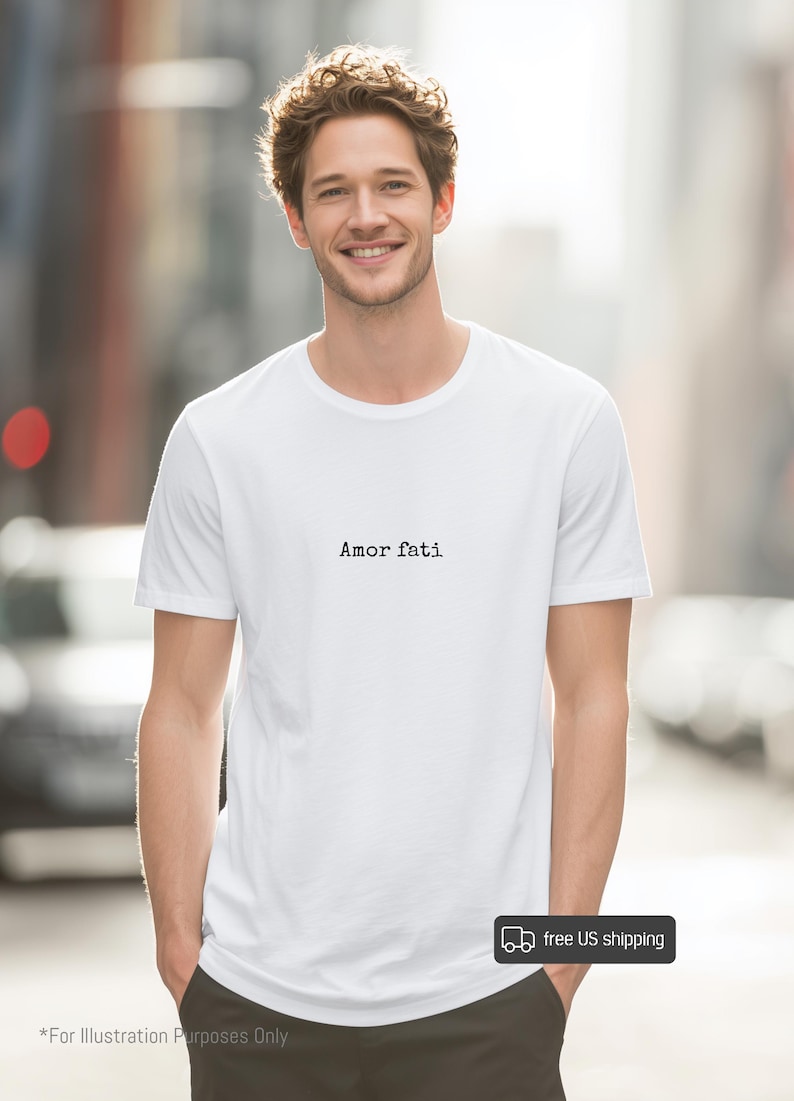 Peut inclure: Un t-shirt blanc &agrave; manches courtes avec le texte Amor fati imprim&eacute; en noir dans une police de style machine &agrave; &eacute;crire au centre de la poitrine. Le v&ecirc;tement pr&eacute;sente une encolure ronde classique et un ourlet droit pour un aspect &eacute;pur&eacute;.