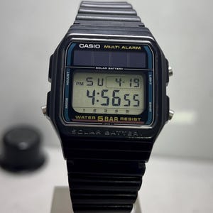 Può includere: Orologio digitale Casio nero con quadrante rettangolare. L'orologio mostra l'ora, la data e il testo "MULTI ALARM". L'orologio ha un cinturino nero e il testo "WATER 5 BAR RESIST" è visibile.