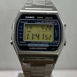 May include: A silver Casio digital watch with a black face and a digital display showing the time and date. The watch has a stainless steel band and features multiple function buttons. The watch face reads "CASIO" and "Water Resist 100M".