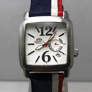 May include: A silver-toned Orient watch with a white face, black numerals, and red second hand. The watch has a rectangular case and a fabric band with blue, white, and red stripes. The watch face displays the day and date.