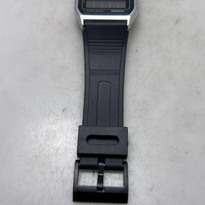 May include: A digital Casio watch with a black strap. The watch face displays the time and date in a digital format. The watch has a silver-colored case and a black buckle.