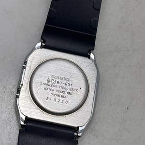 May include: A silver-toned Casio watch with a black rubber strap. The watch back is visible, displaying the Casio logo, model number 520 BB-801, and text indicating a stainless steel back and water resistance. The watch is a classic design.