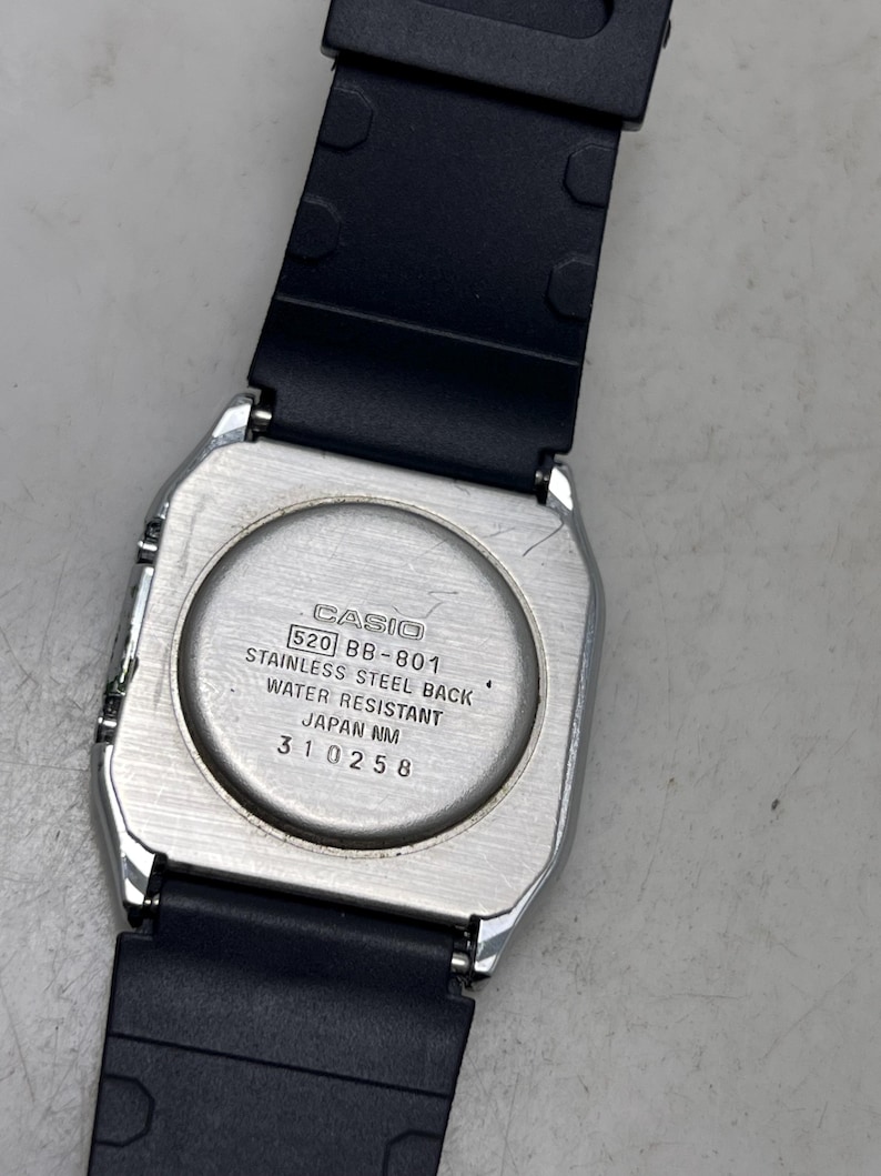 May include: A silver-toned Casio watch with a black rubber strap. The watch back is visible, displaying the Casio logo, model number 520 BB-801, and text indicating a stainless steel back and water resistance. The watch is a classic design.