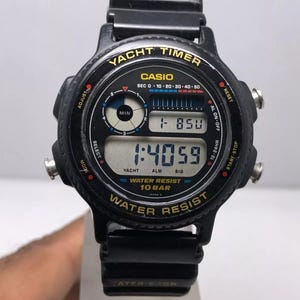 Op de afbeelding: Zwarte Casio Yacht Timer horloge met digitale display. Het horloge heeft een zwarte band en een ronde wijzerplaat met gouden letters. Het toont de tijd en andere functies. Waterbestendig.