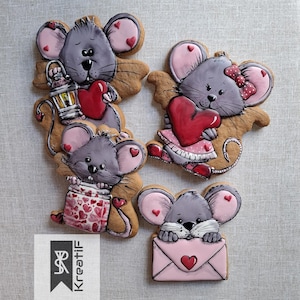Peut inclure: Quatre biscuits décorés en forme de souris. Chaque souris grise a des oreilles roses et tient un cœur rouge ou un pot de cœurs. L'une tient une lanterne, une autre une enveloppe rose avec un cœur, et une autre porte une robe rose.