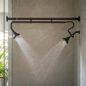 May include: A matte black dual shower head system mounted on a horizontal tension rod. The fixture features two adjustable shower heads, each emitting a steady stream of water, connected by a curved metal arm assembly against a tiled wall.