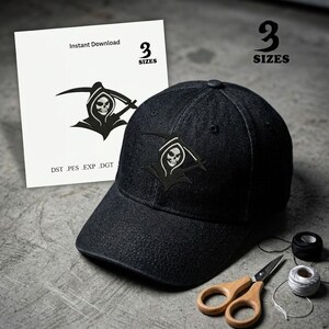 May include: A black denim baseball cap with a Grim Reaper design, a white card with the text "Instant Download" and "3 SIZES", and a pair of scissors. The cap has a curved brim and a stitched emblem.